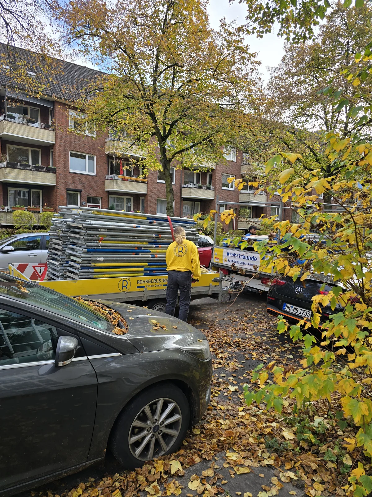 Frau im Rohrfreunde-Pullover beim Verladen von Gerüstmaterial – Rohrgerüstbau Pronin Hamburg